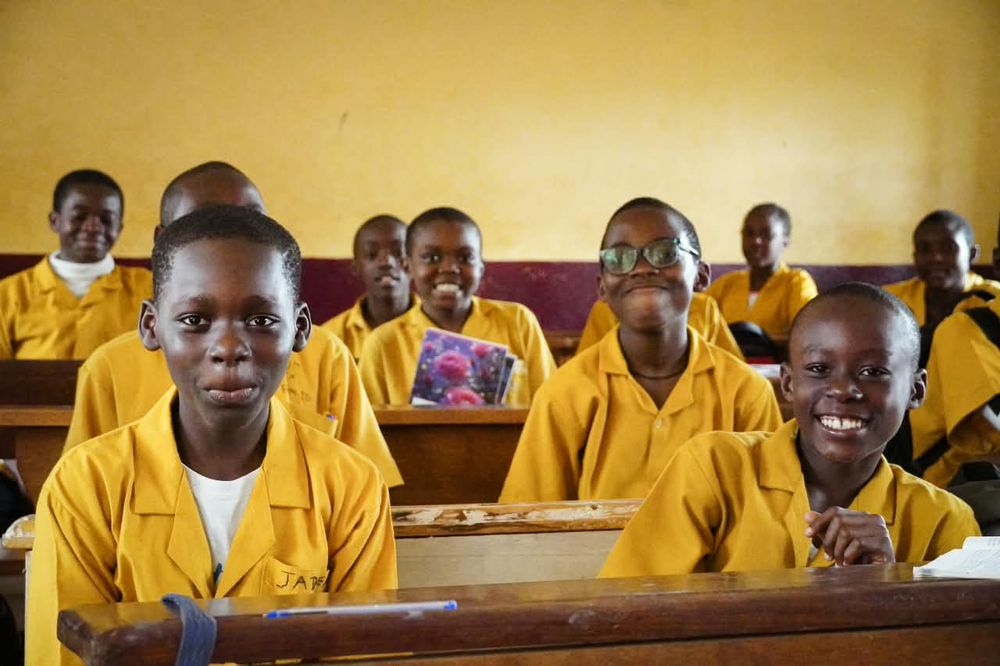 Smiling students in yellow uniforms seated at their desks