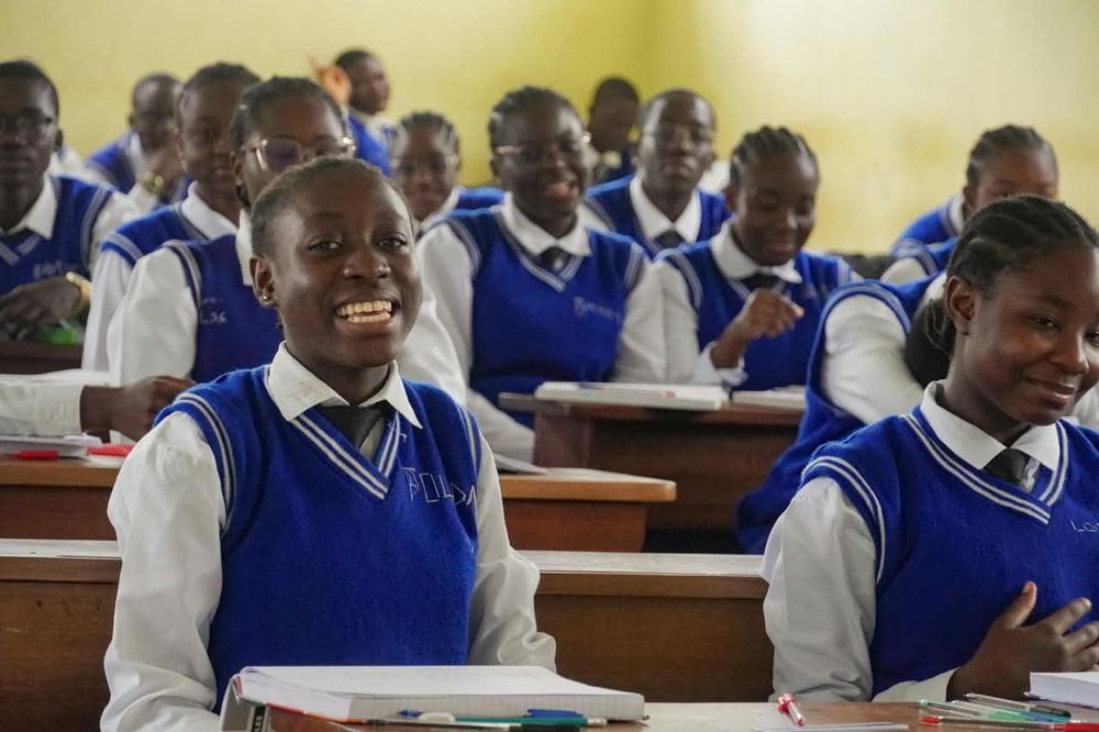 Smiling secondary students in blue uniforms during a lesson