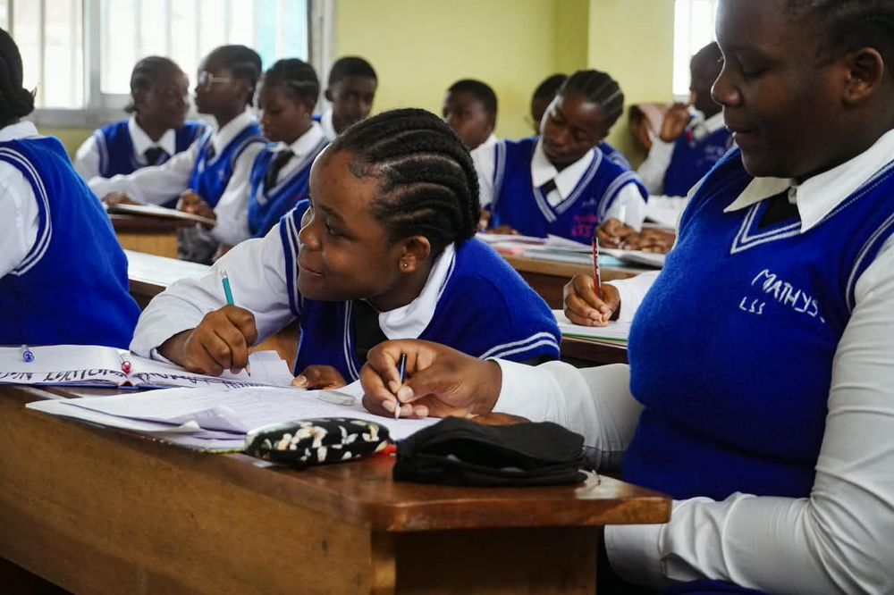 Students in blue uniforms working together at a desk