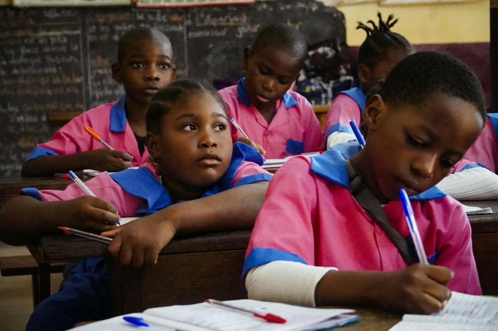 Primary pupils in pink uniforms writing in their notebooks