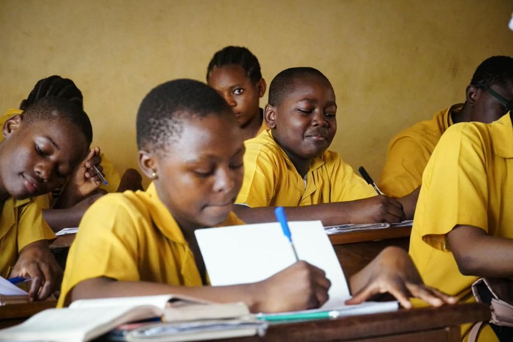 Students in yellow uniforms taking notes in class