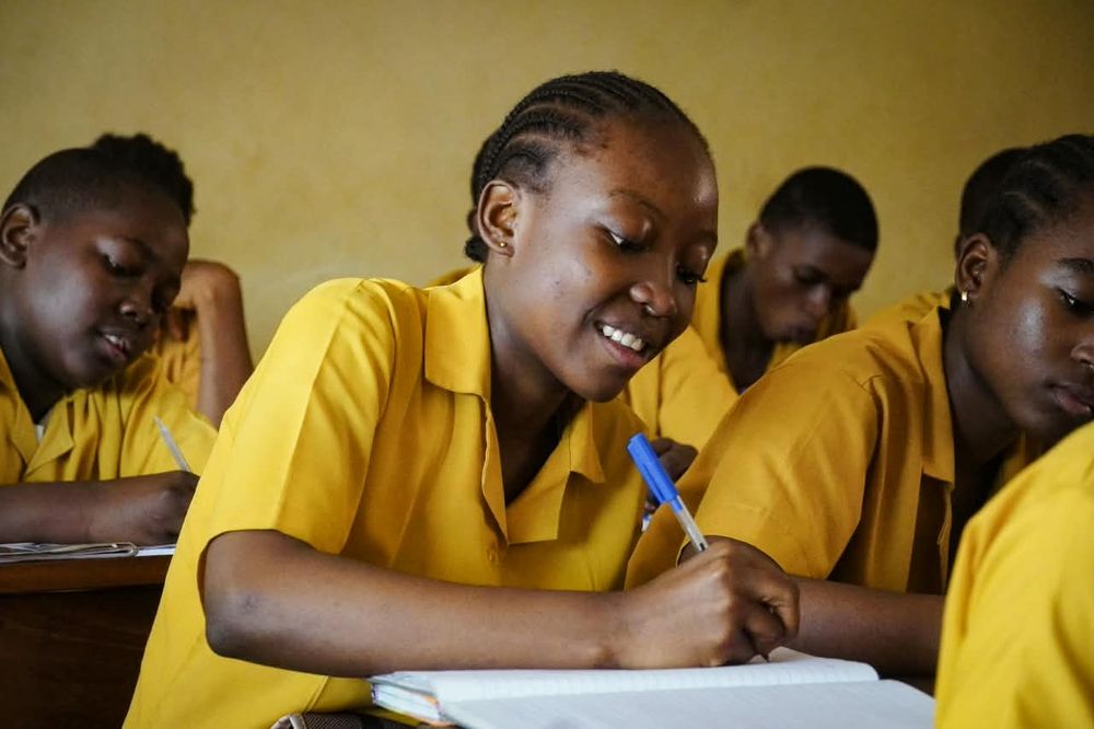 Smiling student writing in her notebook during a lesson