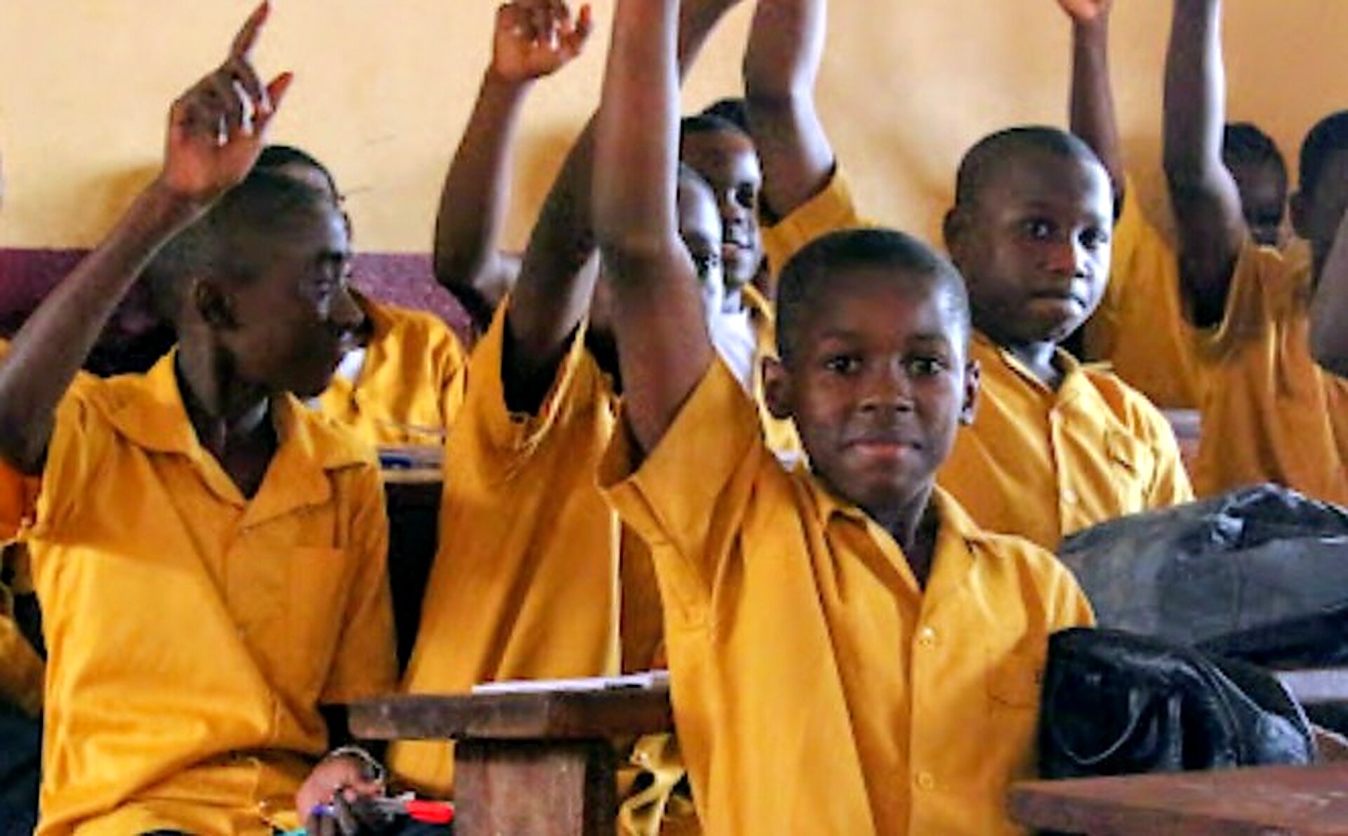 Students raising their hands in a classroom at NES Academic Complex